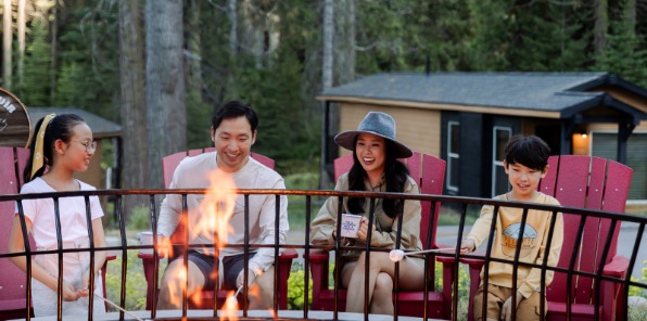 Family toasting marshmallows around fire ring. 
