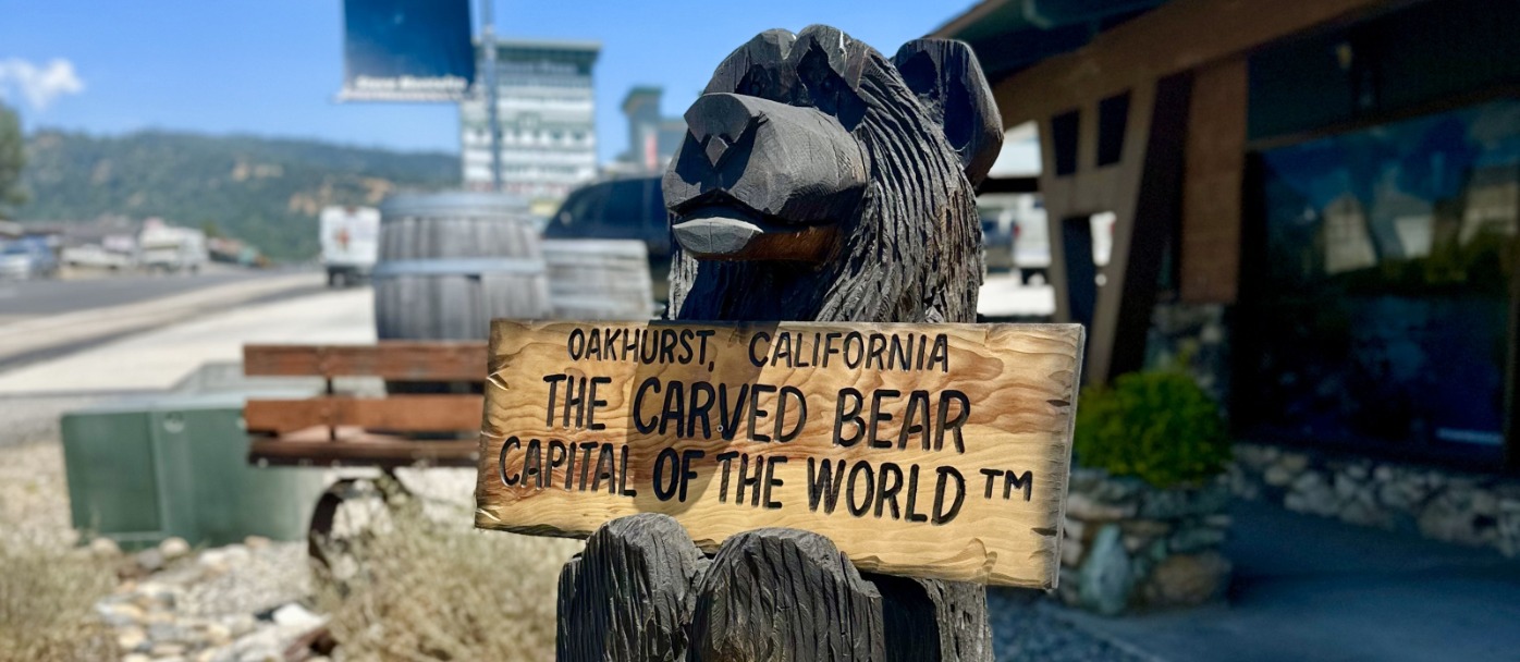Carved Bear holds sign designating Oakhurst, California is the Carved Bear Capital of the World(TM)