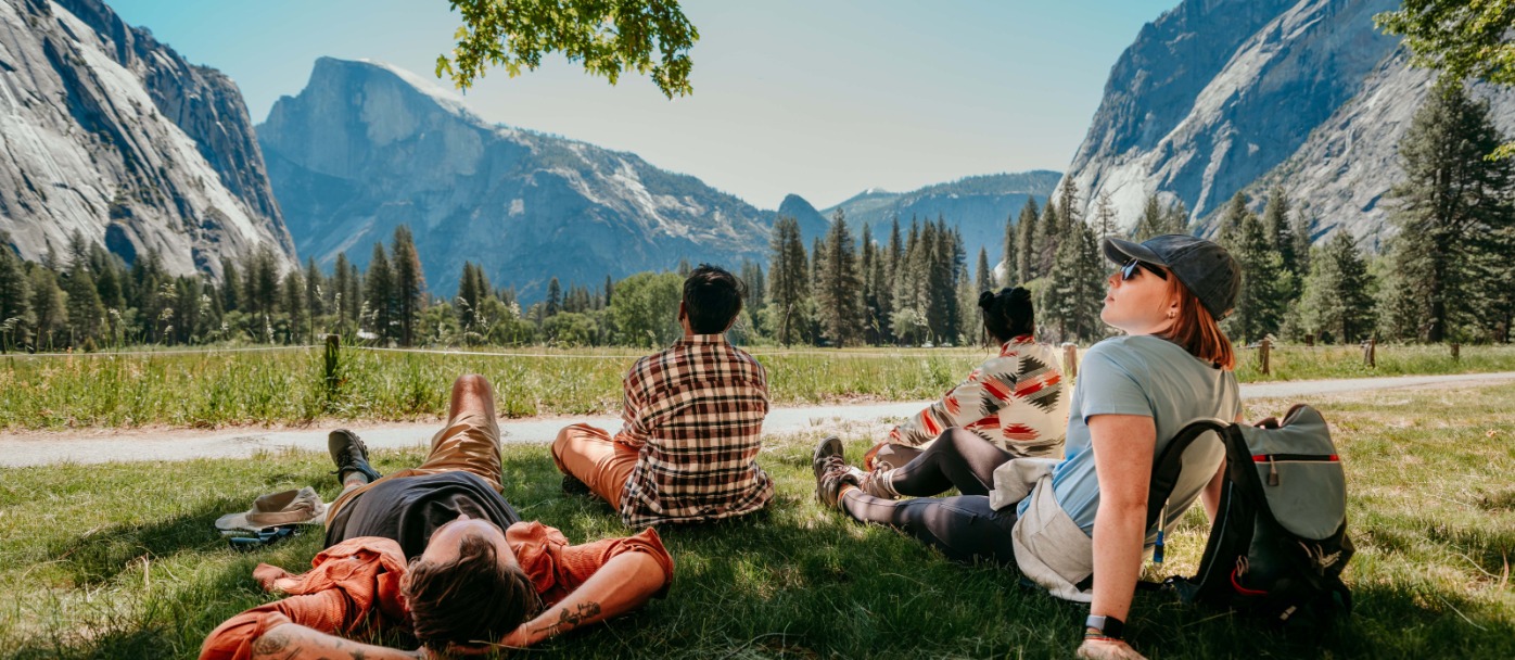 Four friends sit in the shade in Yosemite Valley gazing at Half Dome