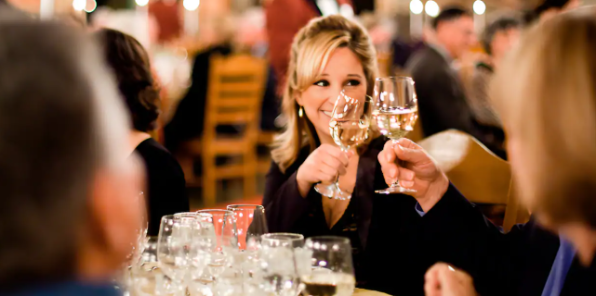 Woman toasting a glass of wine with her friends at the Vintners Event in Yosmeite.