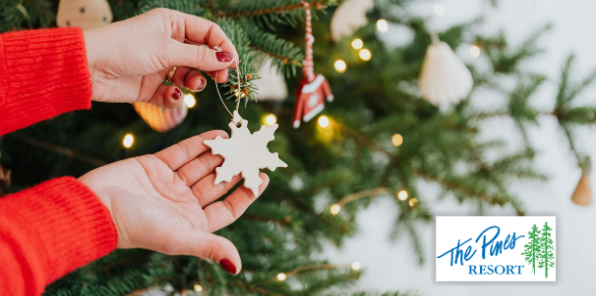 A woman holding a snowflake shaped Christmas ornament.