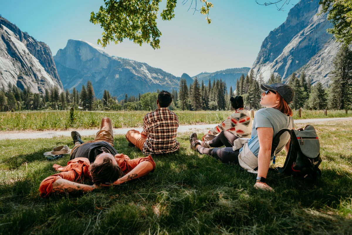 beautiful view of half dome with people in the foreground relaxing on the grass