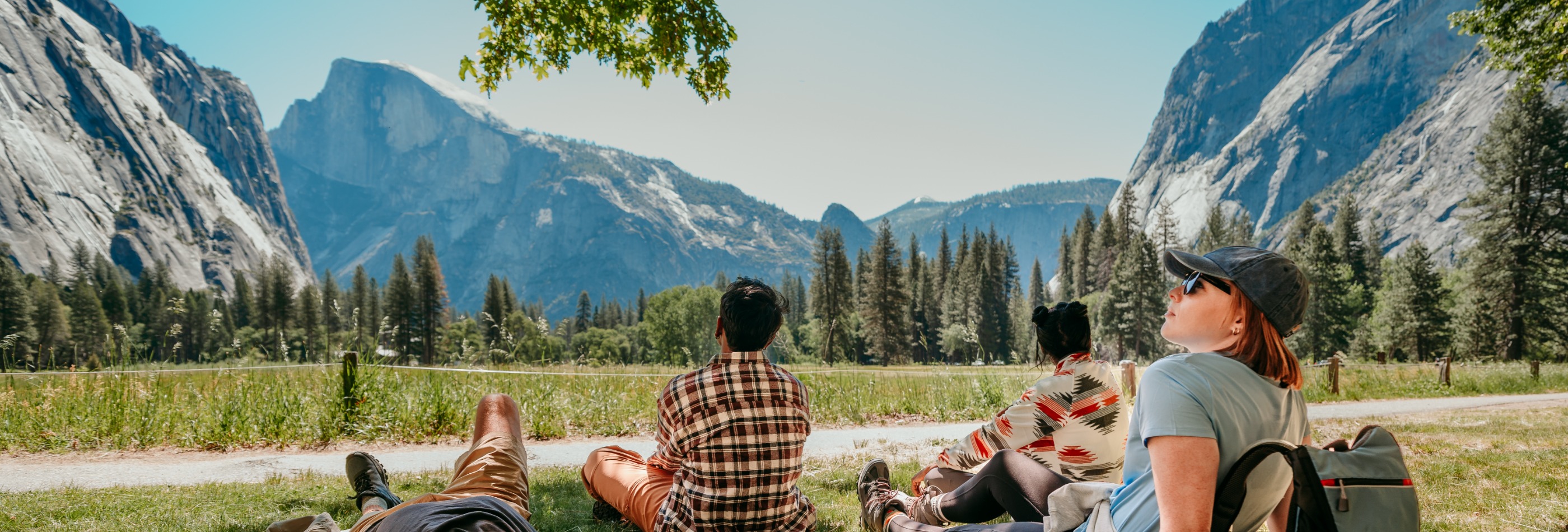 beautiful view of half dome with people in the foreground relaxing on the grass
