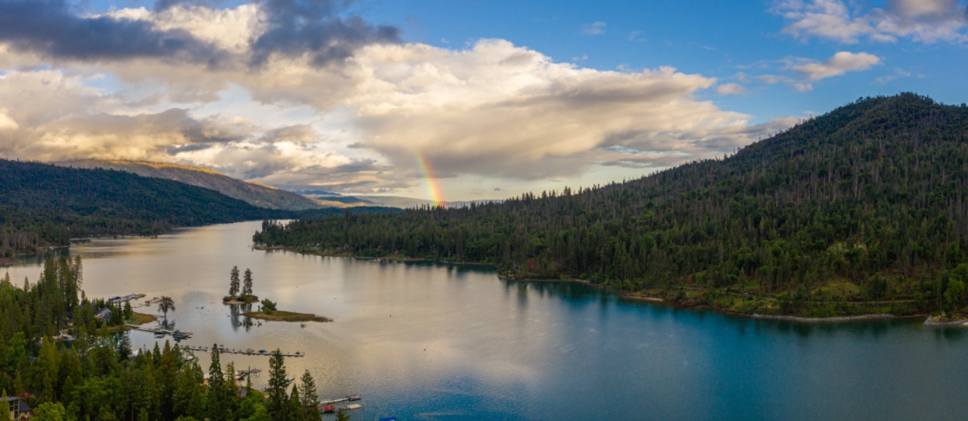 Rainbow breaks through clouds over Bass Lake, CA, and Goat Mountain